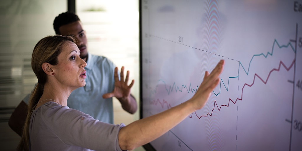 People looking at a price index/earnings graph going upwards and discussing 