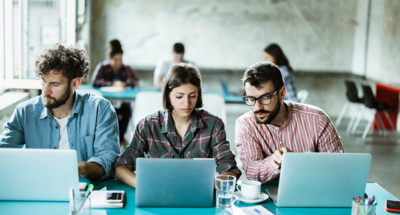 Team of young programmers cooperating while working on computers in the office