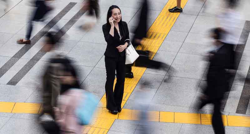 Woman talking on the mobile phone surrounded by commuters