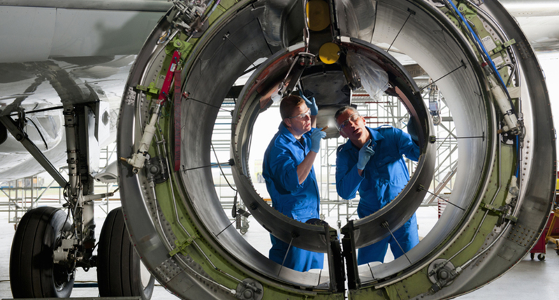 Two engineers in blue overalls discussing workforce management