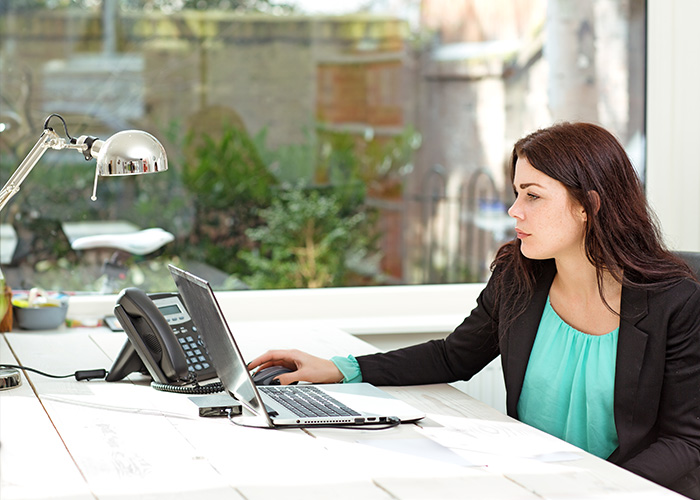 Woman working at a desk with a laptop and chrome lamp