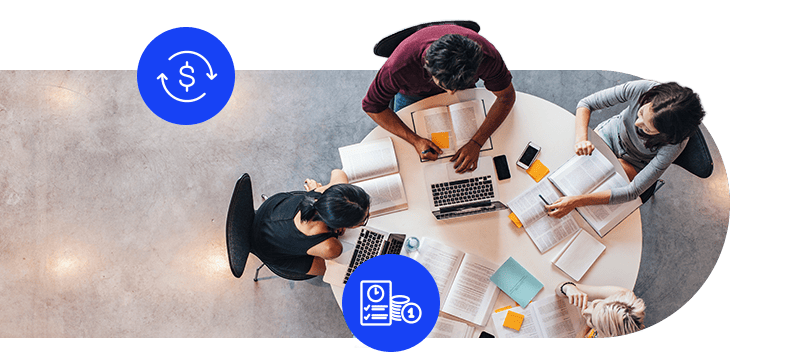 Project team collaborating around a table with laptops, notebooks, and documents during a planning session.