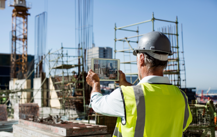 male architect photographig construction site on tabelt device