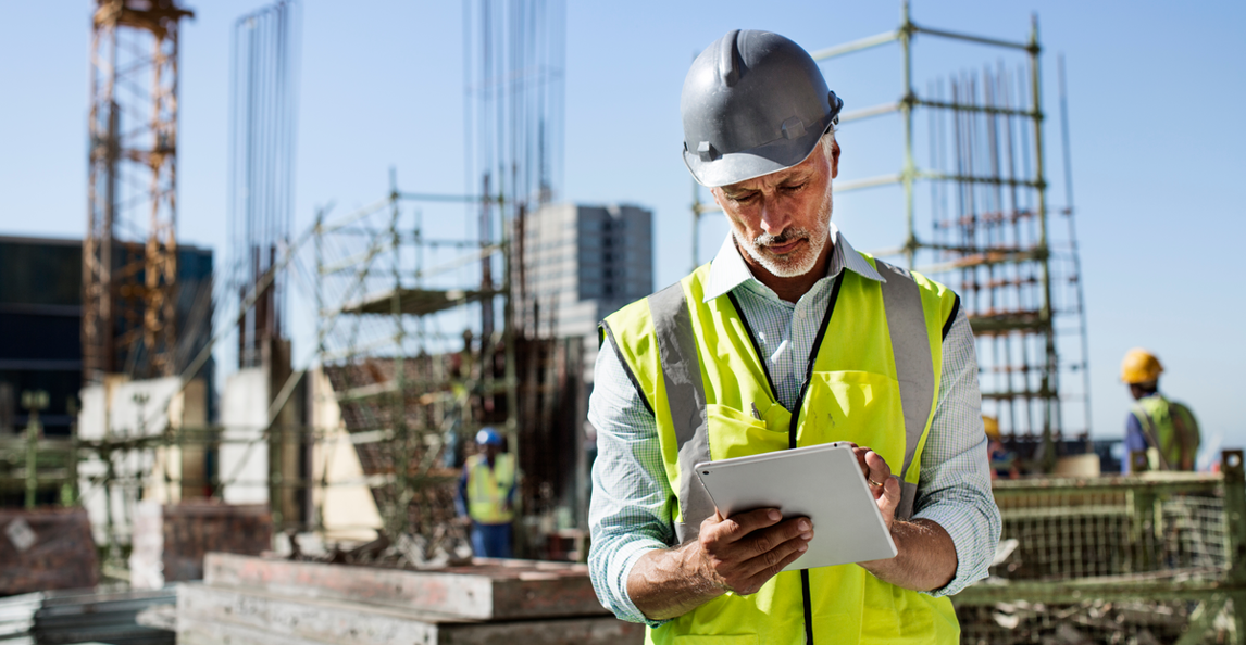 A&E professional using a tablet on an active construction site