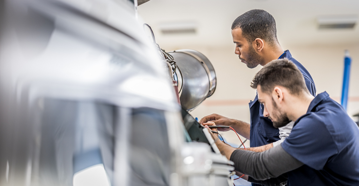 Aerospace maintenance engineers using diagnostic equipment to inspect an aircraft engine during a quality audit