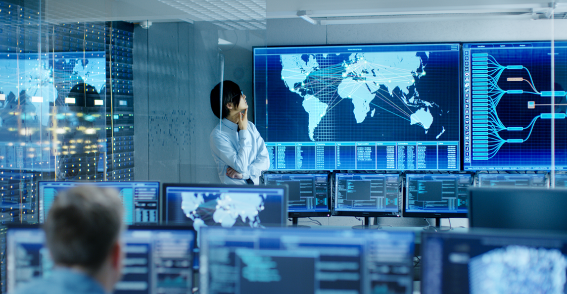 Professional reviewing live intelligence maps across multiple monitors in a high-tech operations centre.