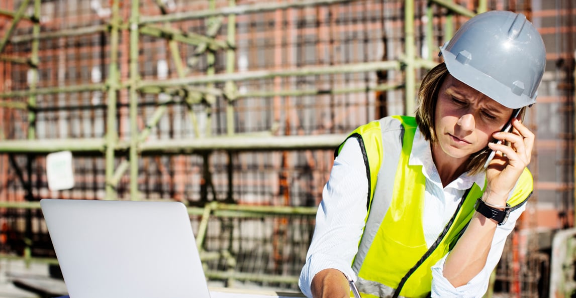 Female construction manager with laptop and plans on site