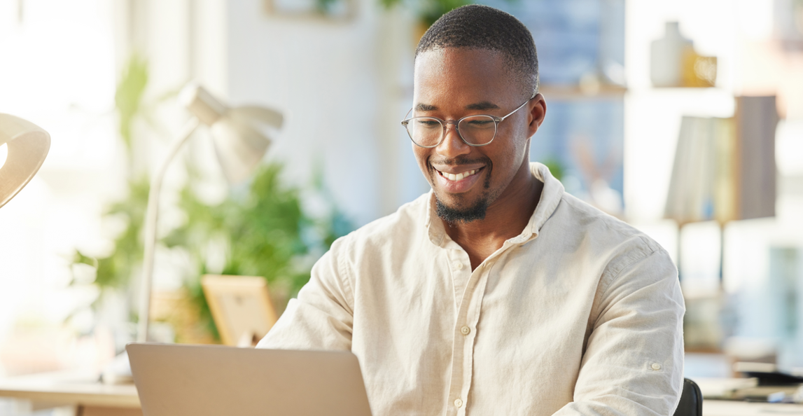 Business professional smiling while working on a laptop in a bright modern office