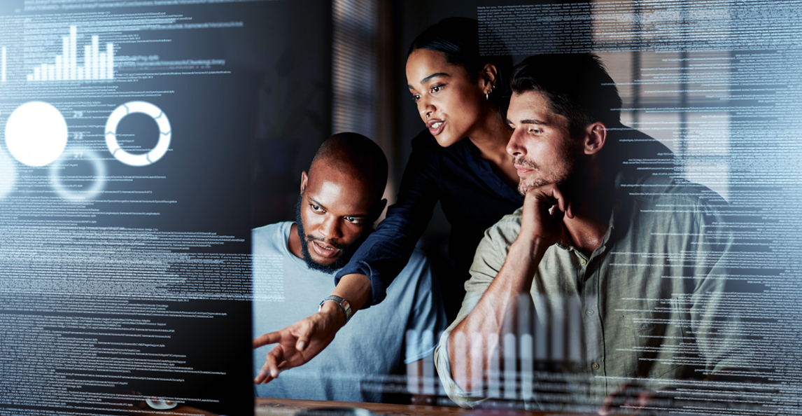 Three business professionals collaborating on data analysis at a computer screen
