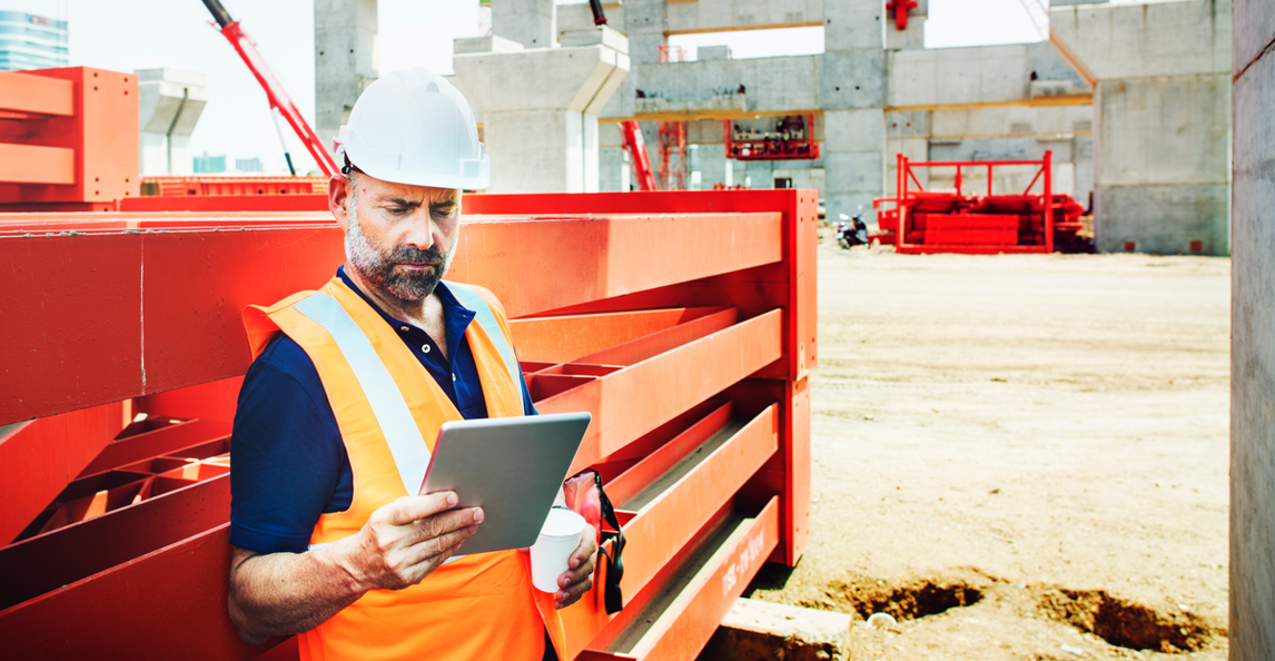 Site manager using a tablet to monitor construction project metrics