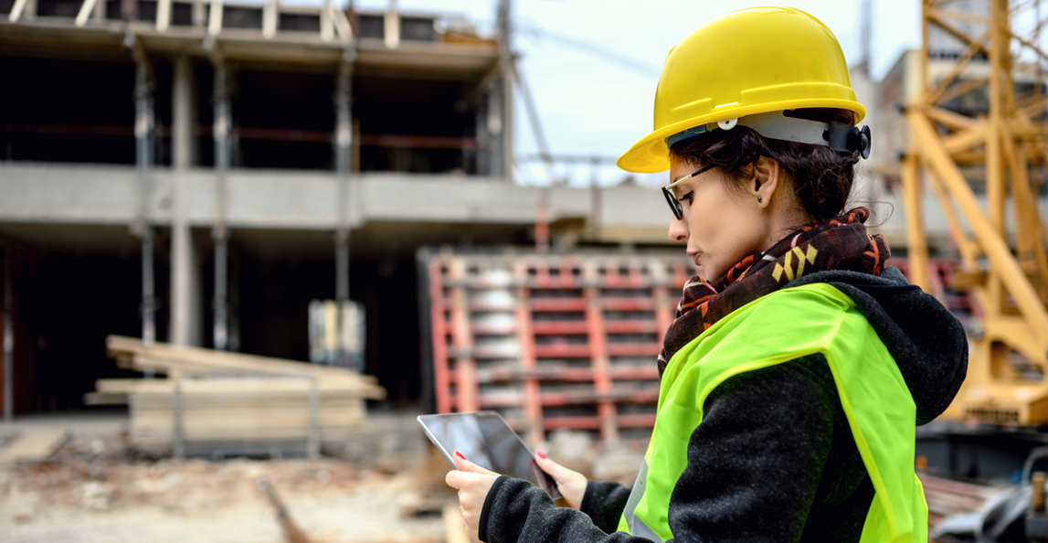 Construction manager reviewing reports on a tablet at an active job site