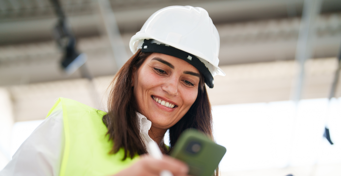 Female construction professional reviewing data on a smartphone at a job site