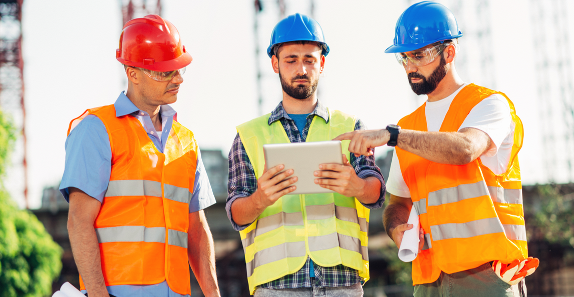 Construction professionals reviewing billing data on a tablet at a job site