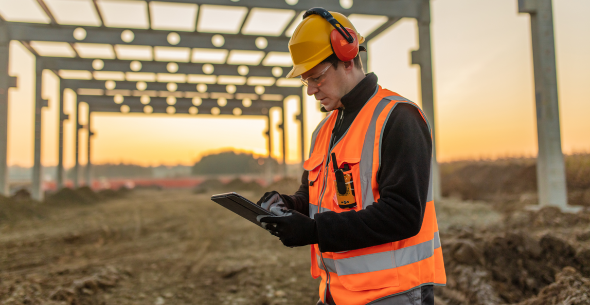 construction worker logging timesheets on tablet job site