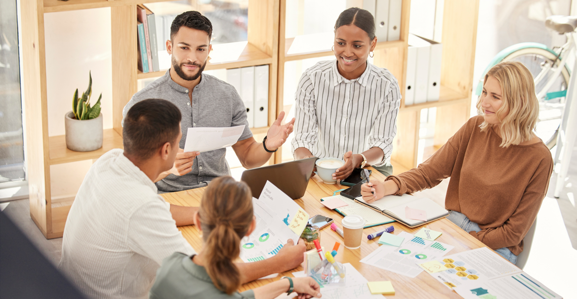 Cross-functional team reviewing reports and charts in a bright office planning session