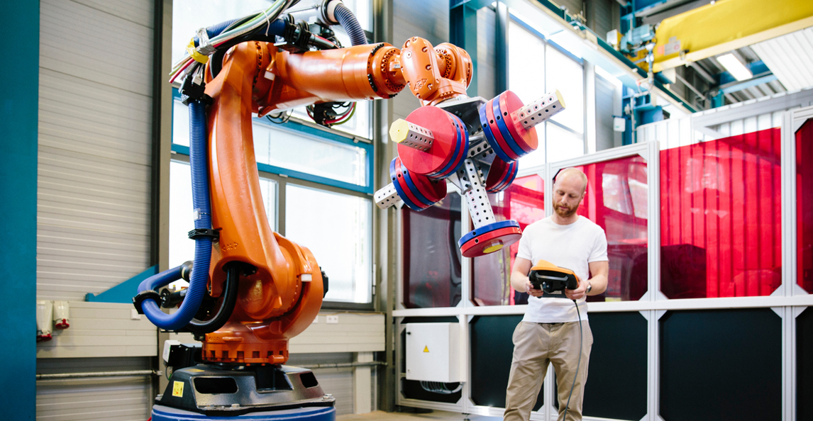 Engineer operating a robotic arm on a discrete manufacturing production floor