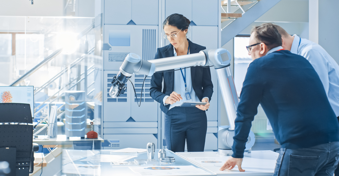 Two engineers programming a robotic arm in a modern manufacturing facility