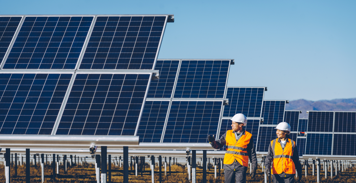 Two environmental consultants in hard hats and high-visibility vests inspecting a solar power station