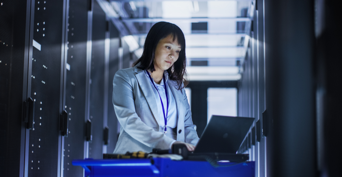 IT professional working on a laptop in a data center to configure cloud ERP integrations.