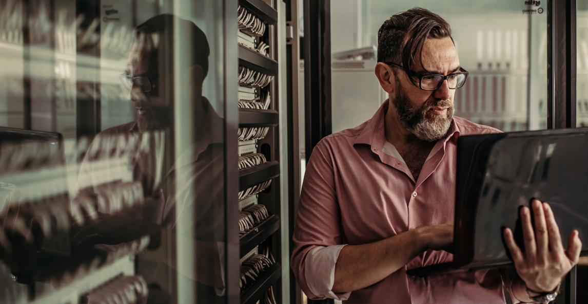 IT professional reviewing a tablet next to a server rack