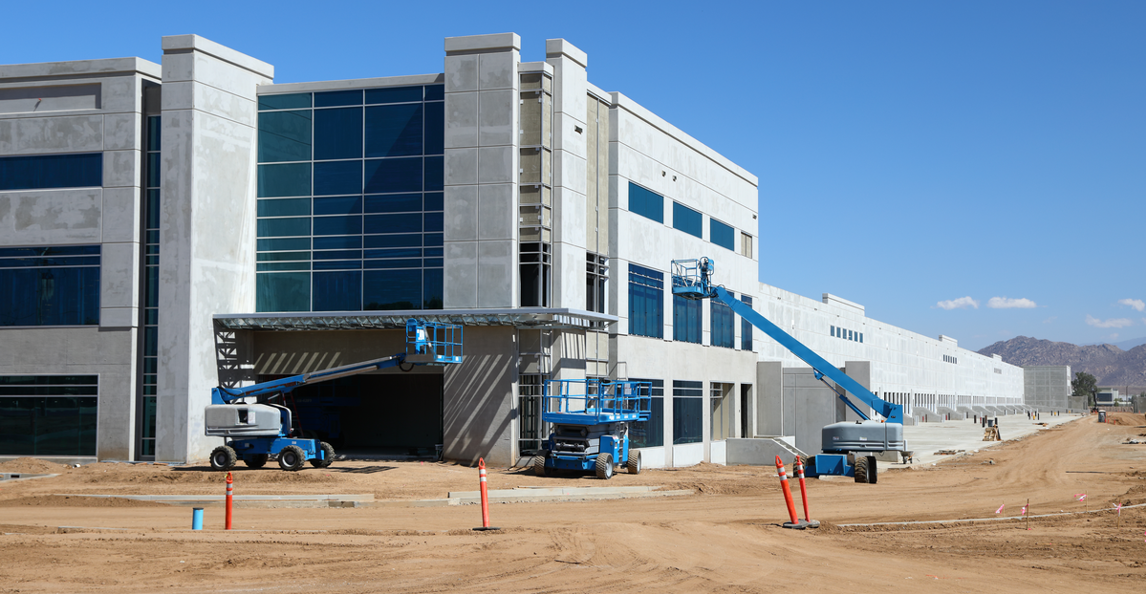 Scissor lifts and boom lifts parked at a large commercial construction site