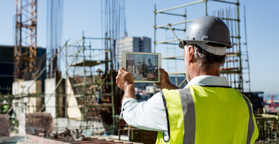 male architect photographing construction site on tablet device
