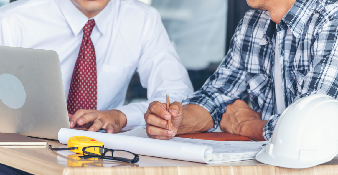 construction manager and contractor reviewing project plans on a laptop