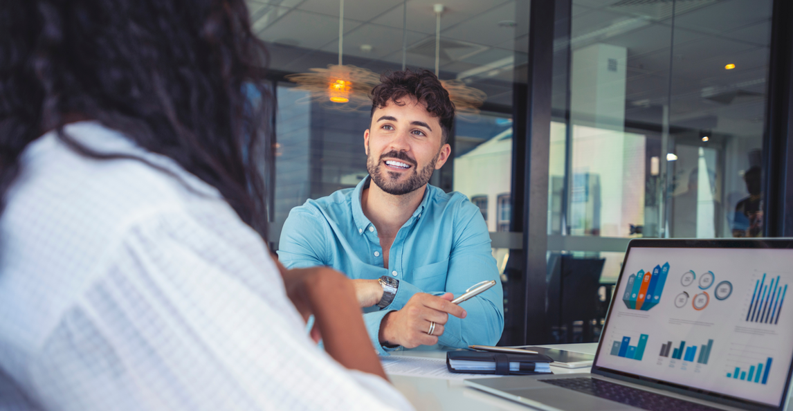 Professional discussing project performance data and charts on a laptop in a meeting