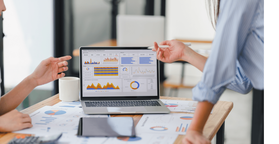 Business team discussing financial charts and metrics on a laptop in an office meeting