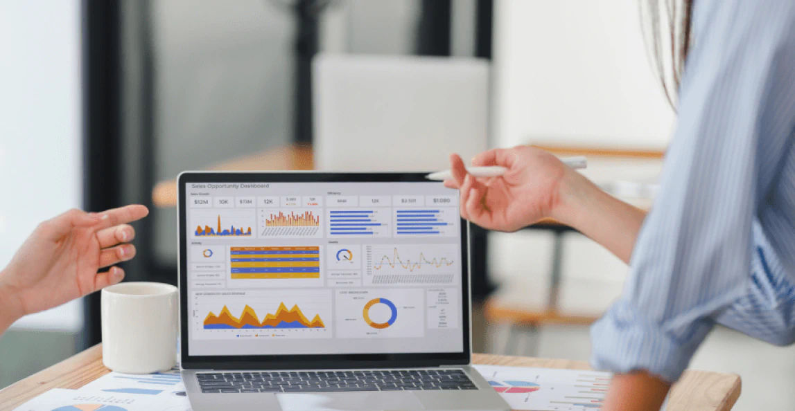Business team discussing financial charts and metrics on a laptop in an office meeting