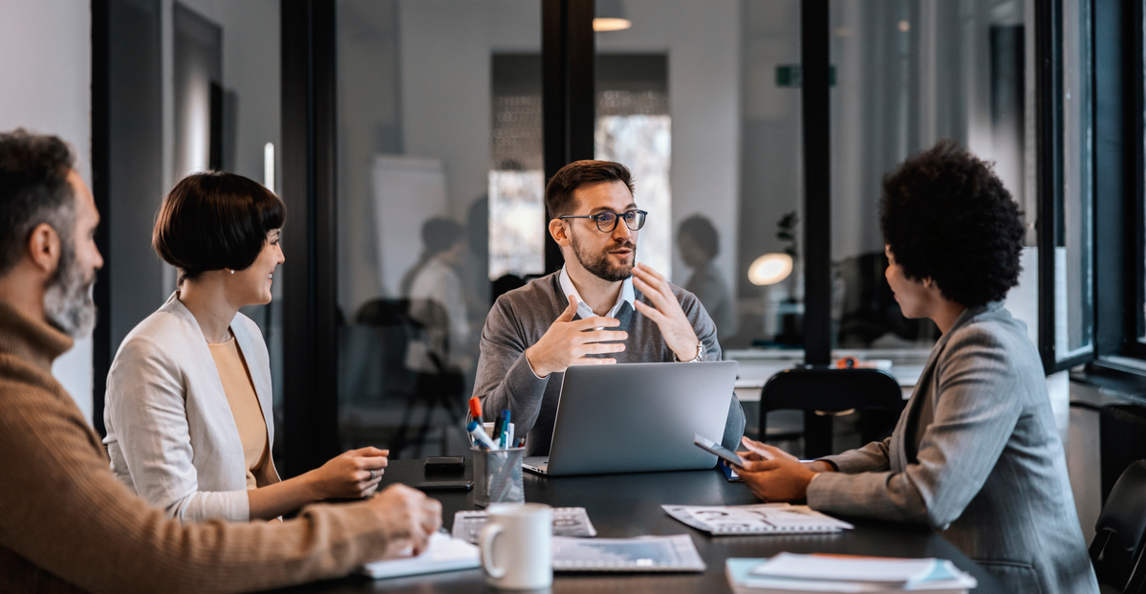 Four professionals collaborating around a table in a modern office meeting room
