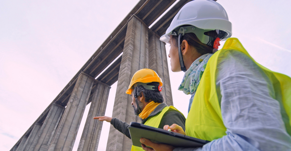 Construction engineers in safety gear inspecting a bridge structure on a public infrastructure project
