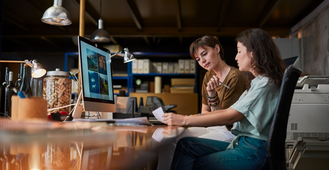 Two professionals collaborating on a computer in a small business office