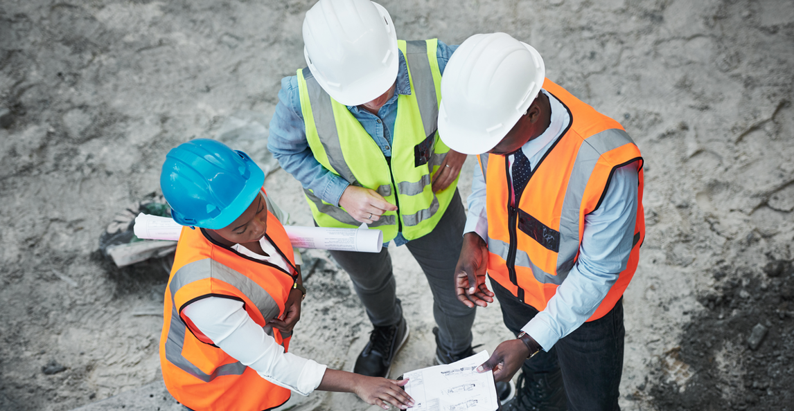 Diverse construction team reviewing project documents at an active job site