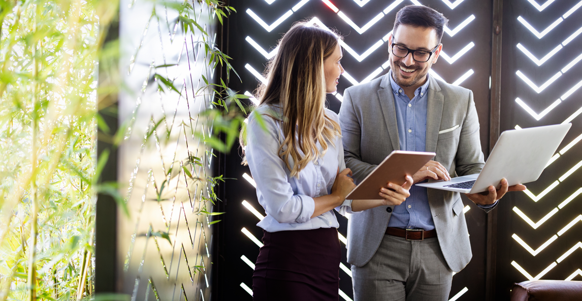 Two business professionals collaborating with a laptop and tablet in a modern office