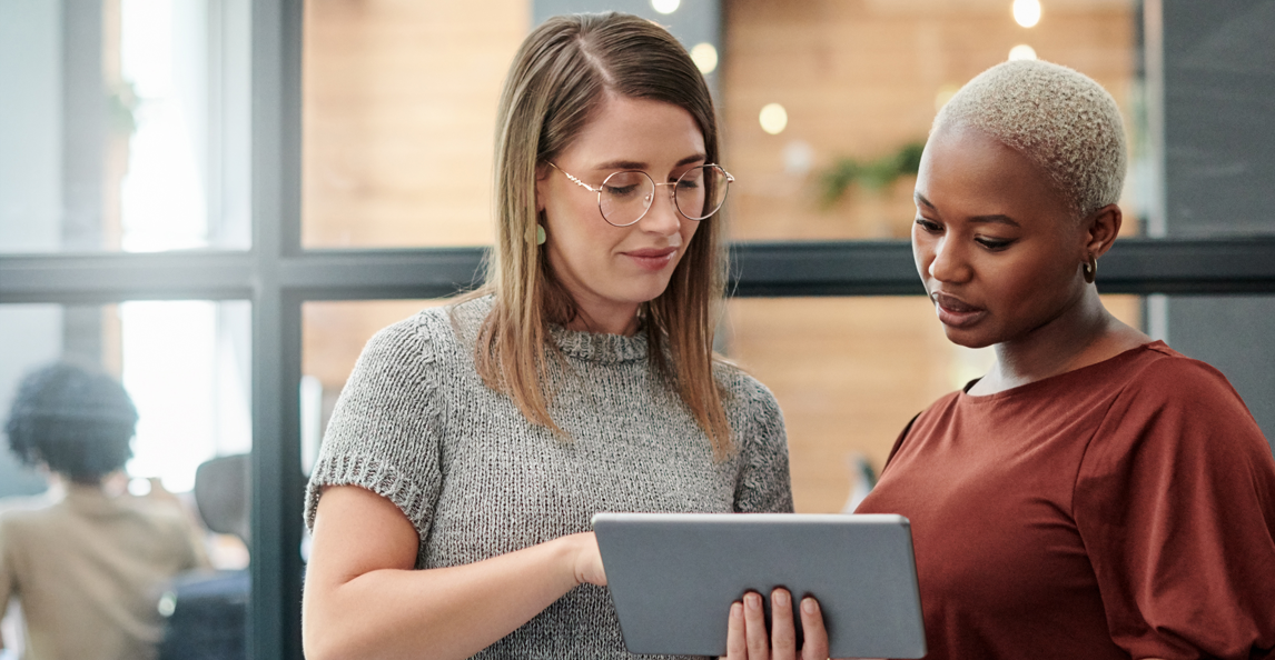 Female colleagues reviewing ERP implementation progress on a tablet in an office