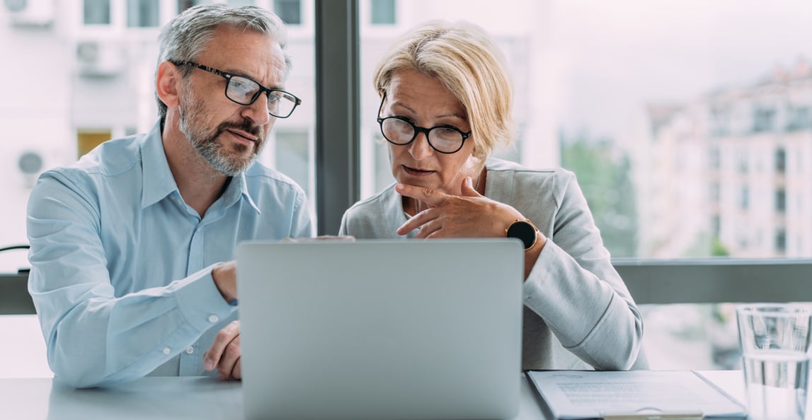 two professionals reviewing data on a laptop