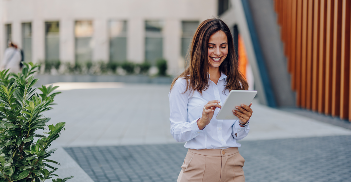 Professional woman using a tablet outside a modern office building