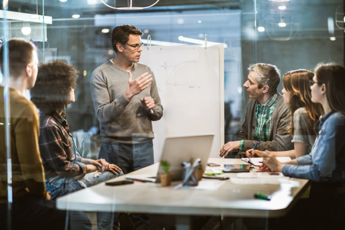 A person presenting and interacting with team members in a meeting room