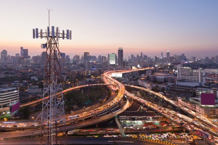Telecommunication tower with a 5G cellular network antenna against a city background
