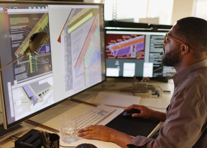 Architect reviewing AI-assisted CAD designs on large monitors