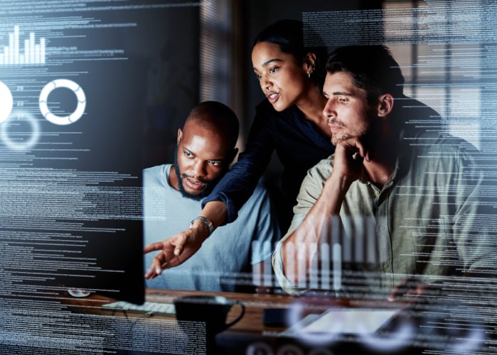 Coworkers looking at data on a large screen in a dark room