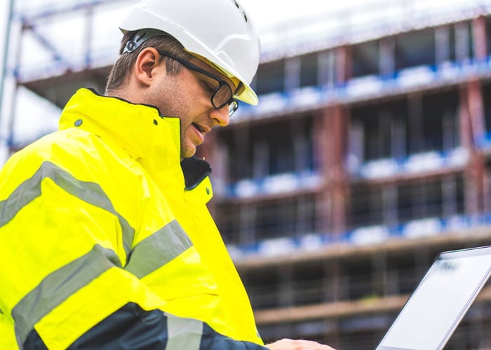 Construction worker on a laptop at a job site