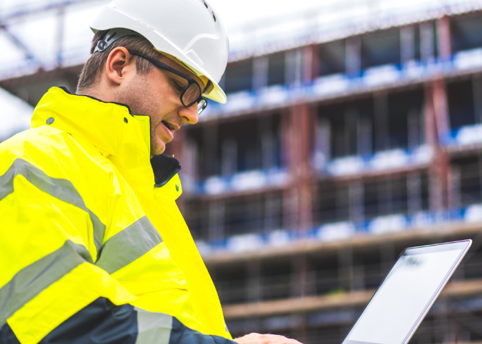 Construction engineer reviewing project timelines on a laptop.
