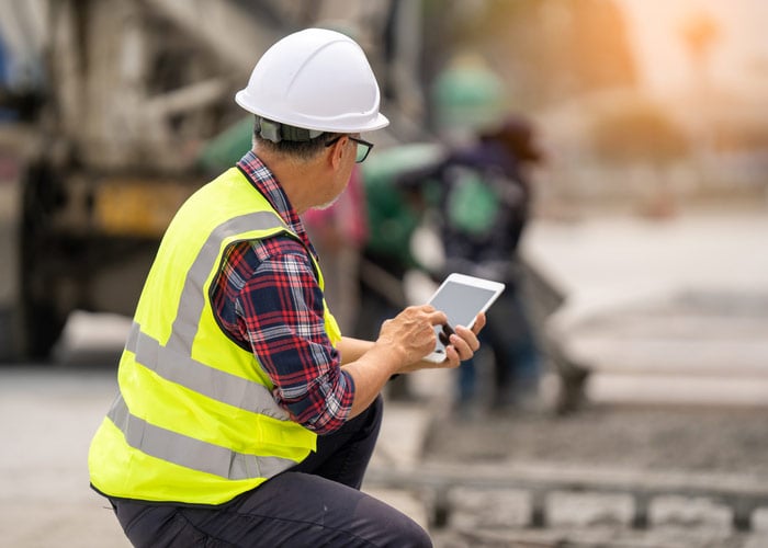 Construction Site Engineer Accessing Project Data on Tablet During Active Build Operations