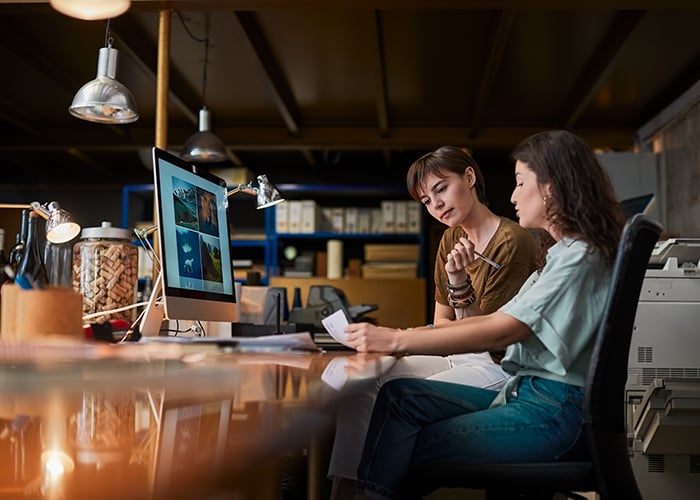Two Creative Professionals Reviewing Design Assets and Visual Content on Desktop Monitor