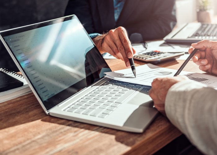 Business Professionals Analyzing Financial Charts and Reports with Laptop
