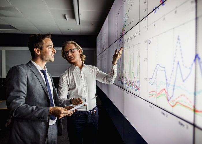 Business people reviewing reports on a large interactive monitor