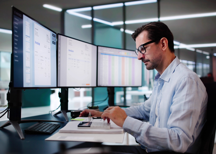 Finance Professional Managing Client Billing and Invoicing Across Multiple Monitors