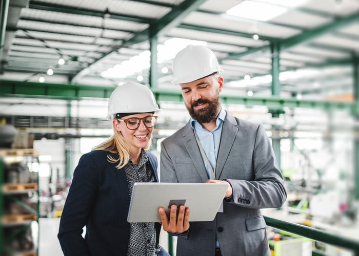 Construction Project Managers Reviewing Work in Progress Data on Tablet at Job Site
